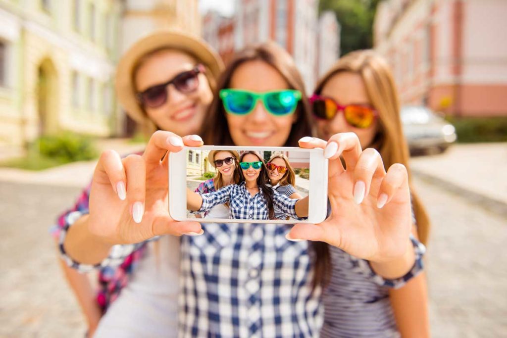 Drei Frauen in Sonnenbrillen machen ein Selfie mit einem Handy