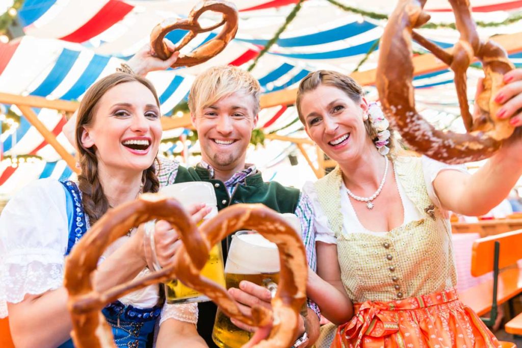 Drei Personen im Bierzelt mit Brezeln und Bier